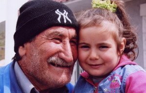 Elderly baseball fan shows off his New York Yankees hat to a granddaughter in Goris.