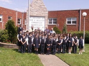 Fourth to seventh graders of the Hovnanian School with members of the Armenian clergy in front of the Monument to the Armenian Genocide in Emerson.