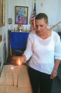 Kulungian lights a candle at St. Gregory Church of North Andover for all those afflicted with breast cancer.