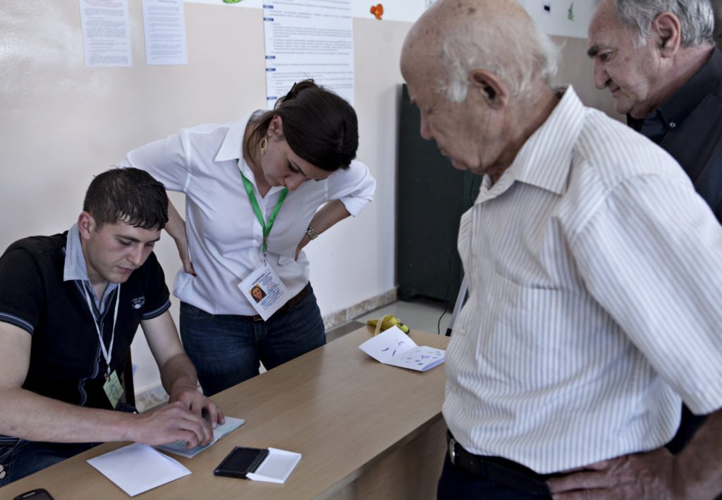 Diasporan Garine Palanjian checks voters' passports to confirm their identity. 