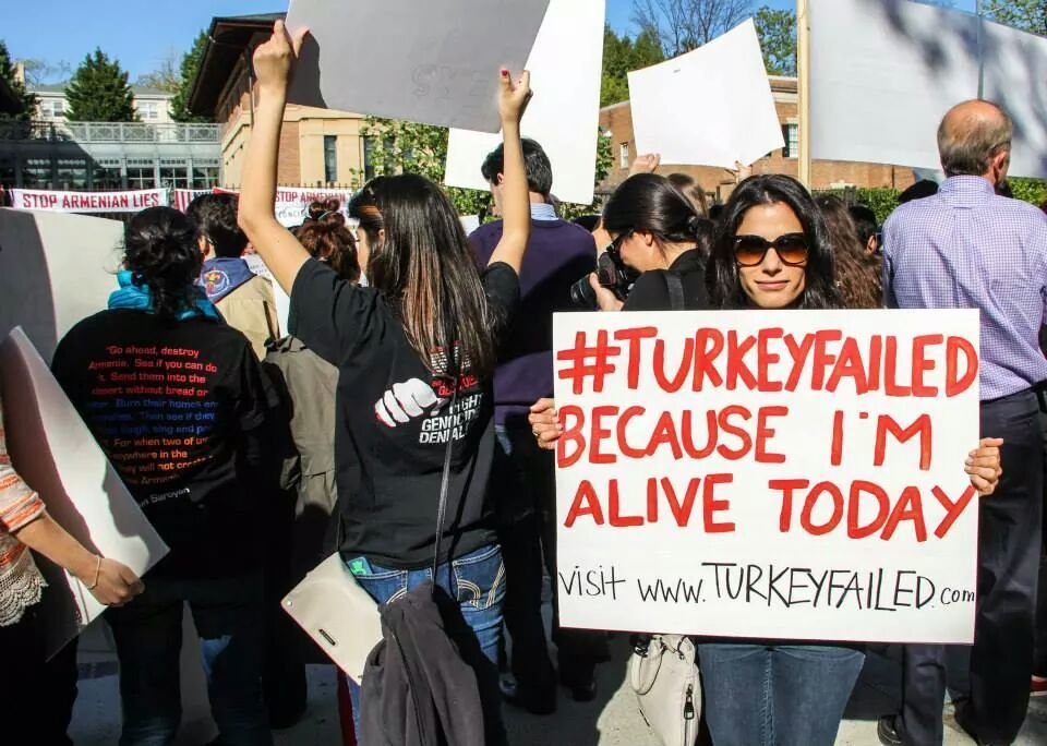 A protester holds a sign that reads, "#TurkeyFailed becuase I'm alive today."