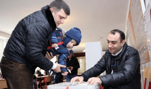 A child helps his father cast his ballot in Sunday's referendum (Photo: ArmenPress)