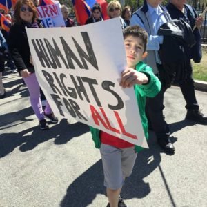 A child holds a poster that reads, "Human rights for all." (Photo: Kenneth Martin)