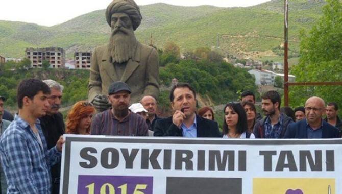 Badem speaking in front of a poster calling for the recognition of the Armenian Genocide