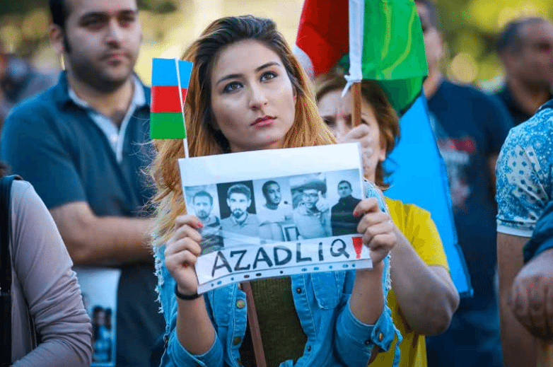 A protester holds a sign calling for the release of unjustly imprisoned youth activists in Baku (Photo: Azadliq Radiosu/RFERL) 
